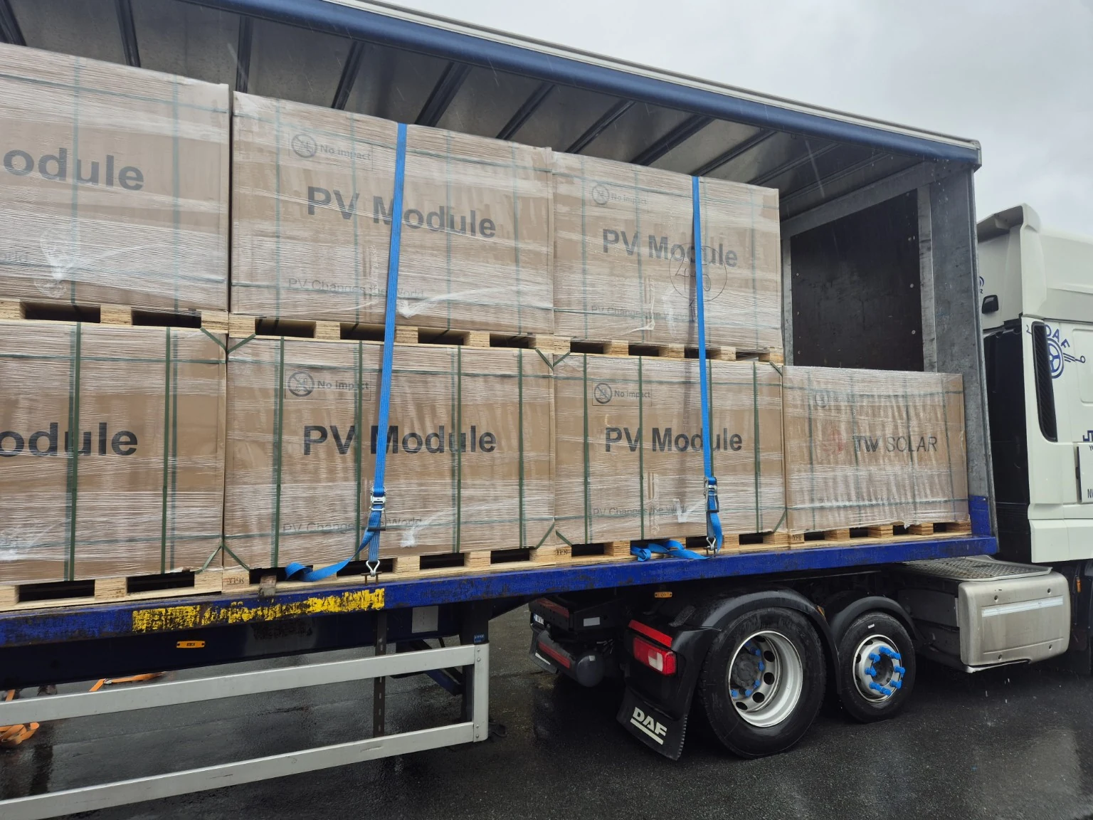 Wrapped palletised equipment photographed on an open curtainsider trailer.